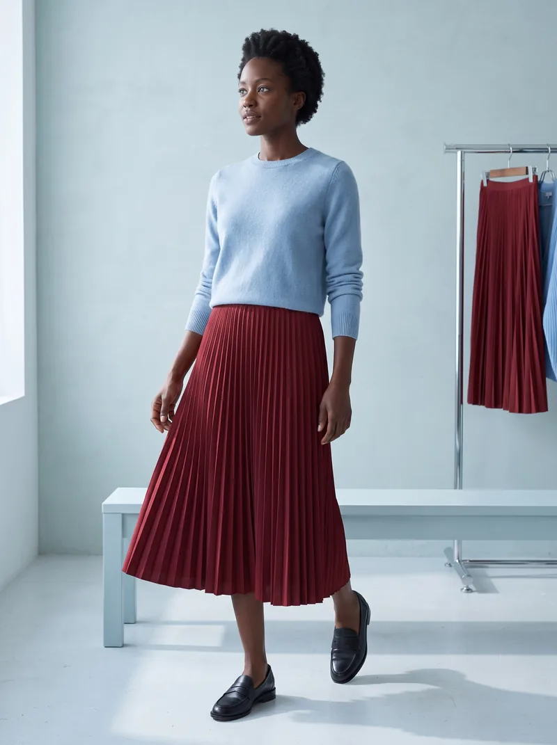 Weekend styling study: a woman in a blue sweater, oxblood pleated skirt and black loafers